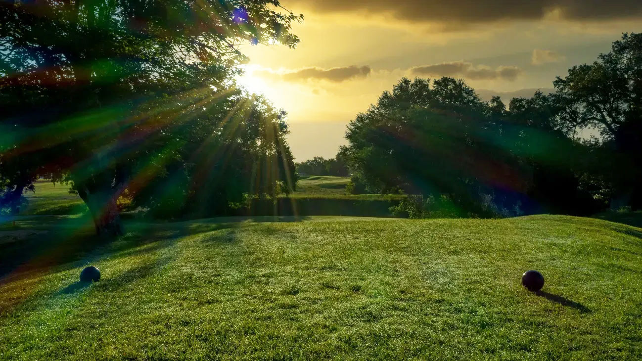 Tee box drenched in sunlight with rays beaming through the trees