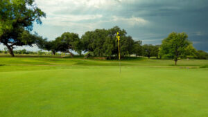 Close up of checkered flag pin on green with sun rays beaming through the clouds