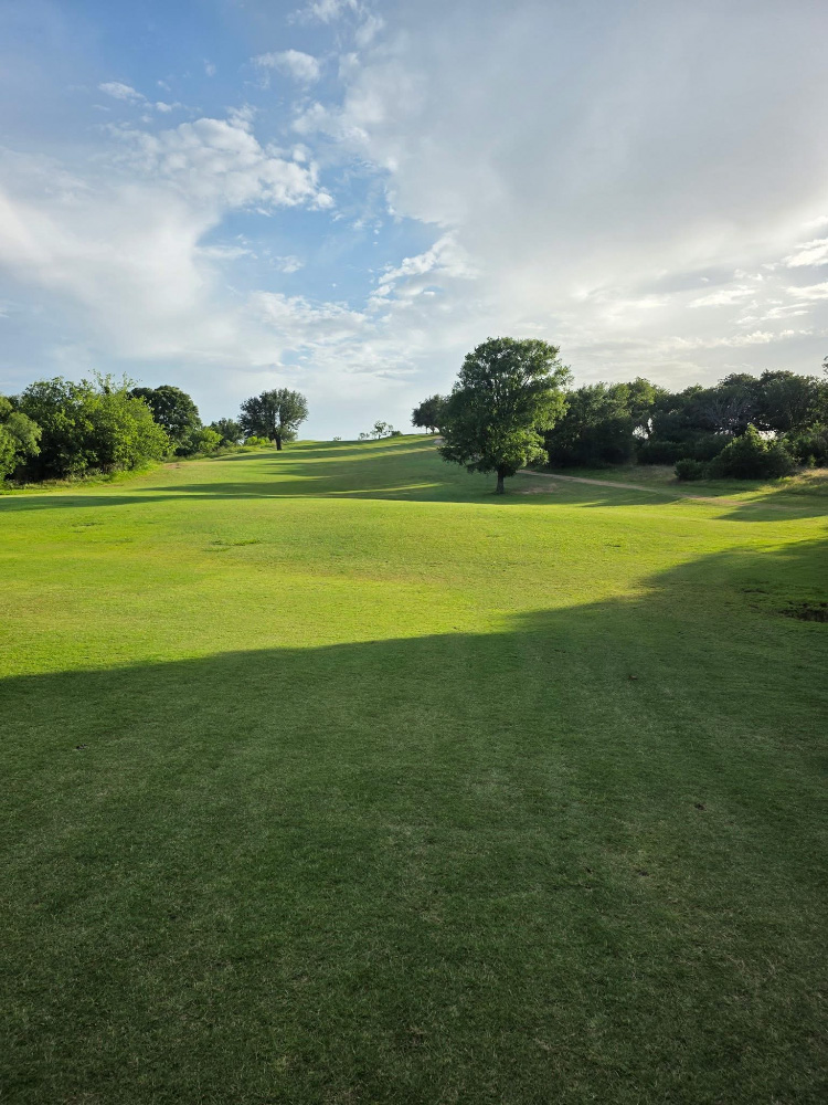 Fairway in shade and sun with blue sky and clouds in the background